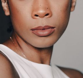 A close up of a woman 's face wearing a white tank top