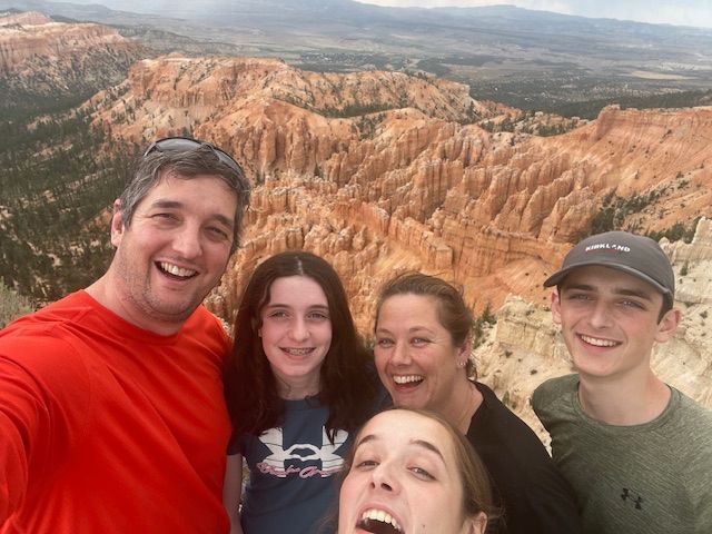 Family smiles for a selfie overlooking Bryce Canyon's red rock hoodoos.