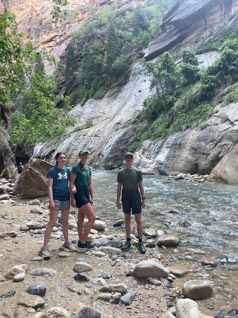 Three people standing in a river canyon with rocky walls.