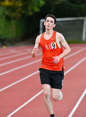 Male runner in orange singlet and black shorts on a track; number 9.