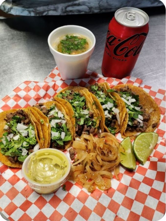 A close up of three tacos on a plate with vegetables.