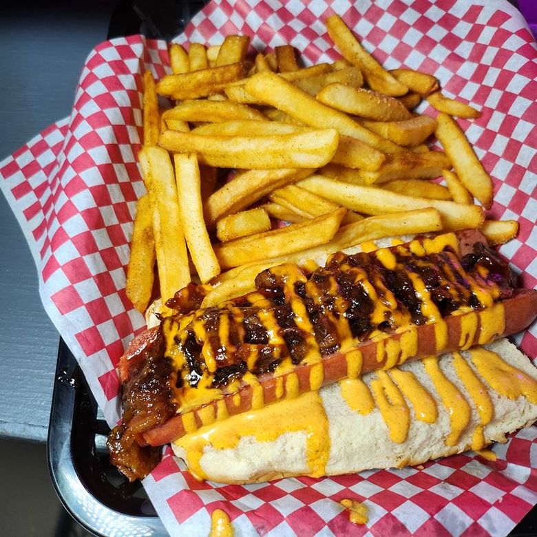 A hot dog and french fries in a basket on checkered paper.