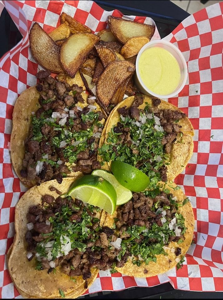 A basket of tacos and potato wedges on a checkered paper.