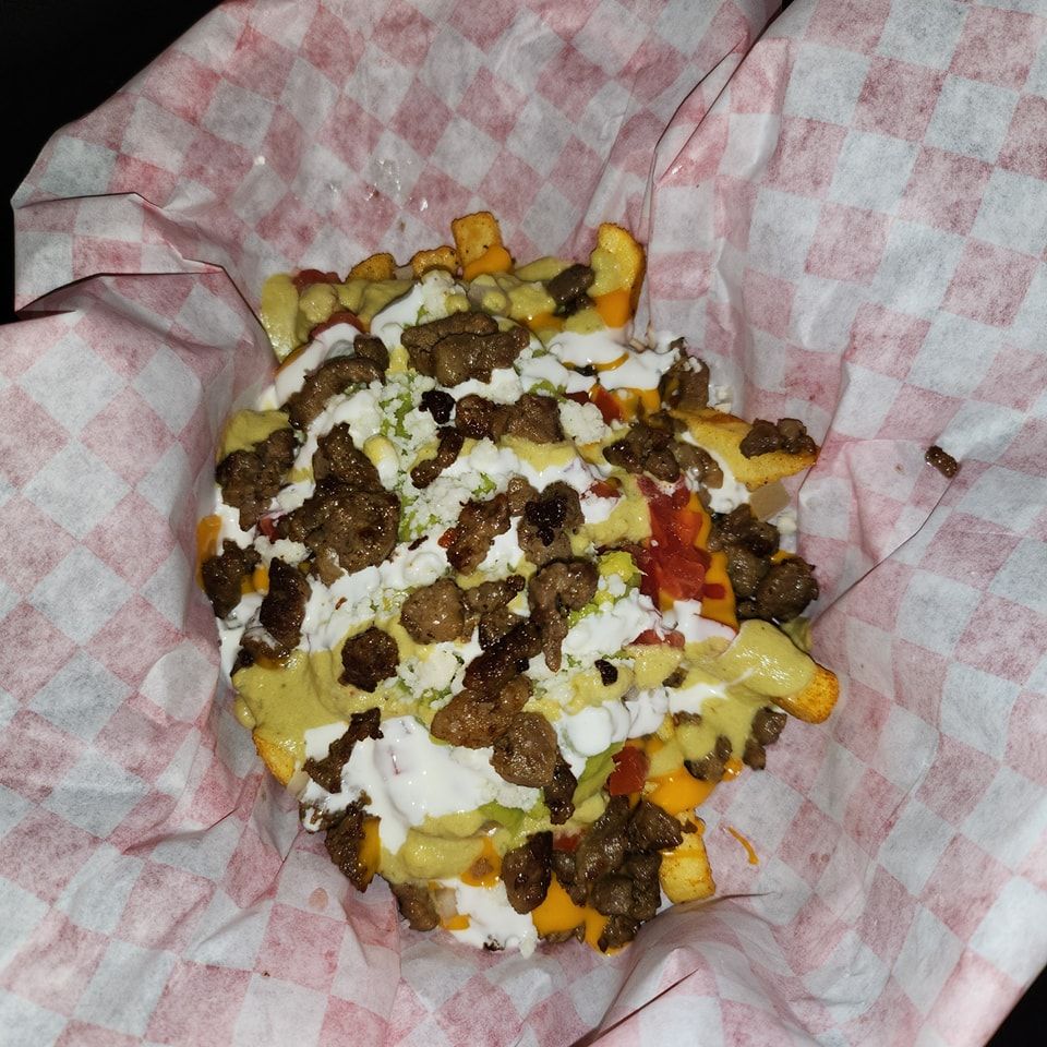 A close up of a french fries covered in cheese and meat