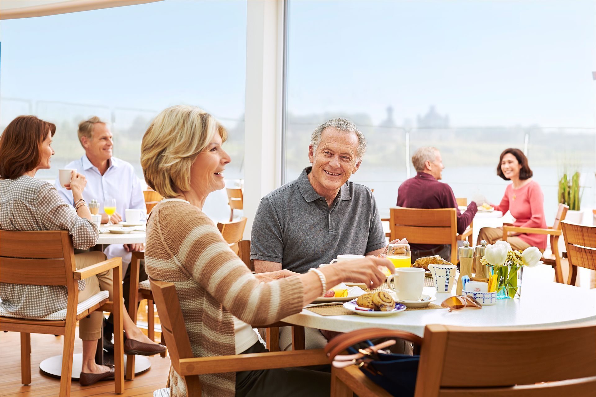 A cruise ship is docked in front of a city on a river.