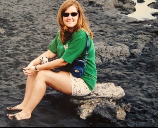 A woman in a green shirt is sitting on a rock