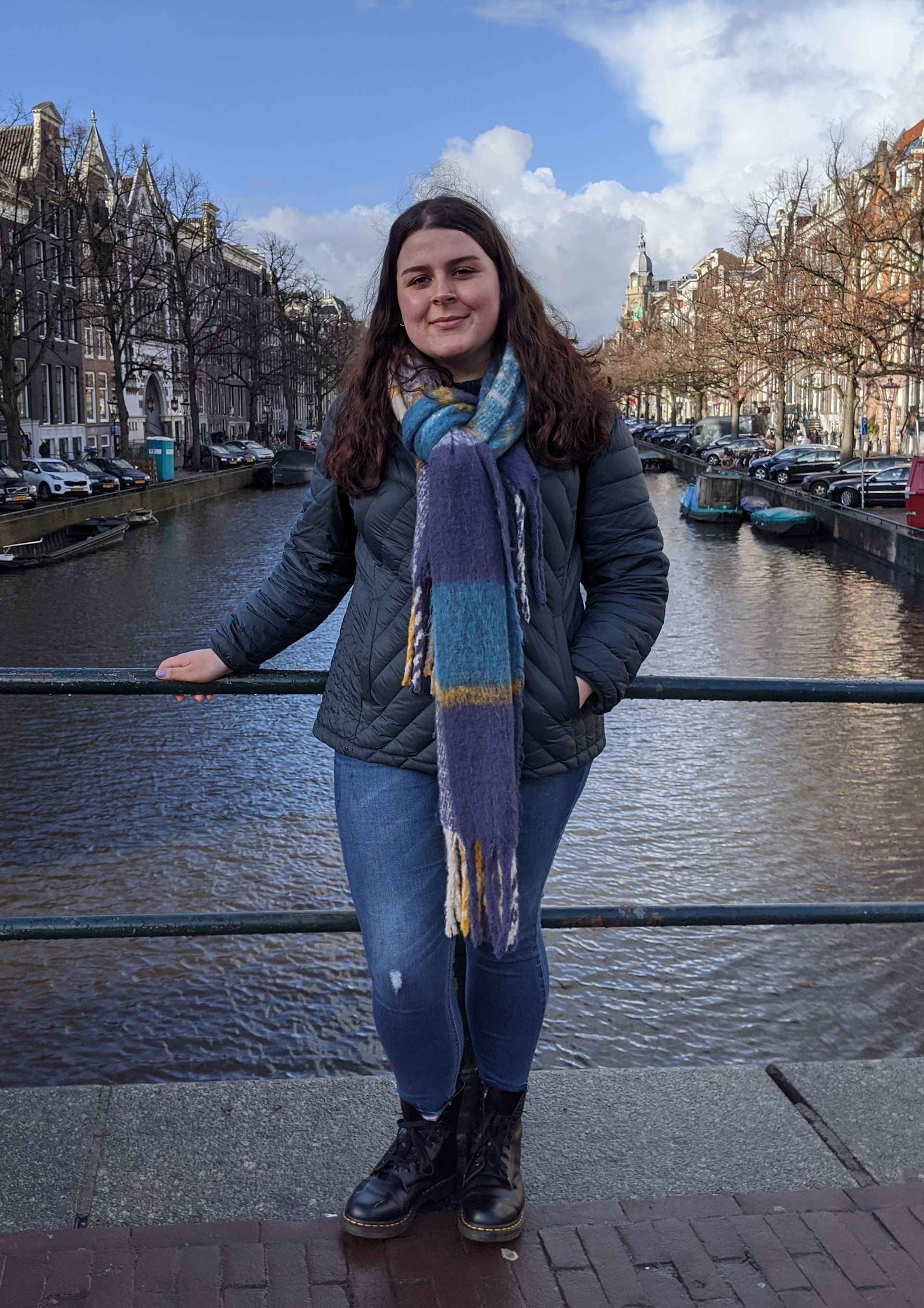 A woman is standing on a bridge over a river.