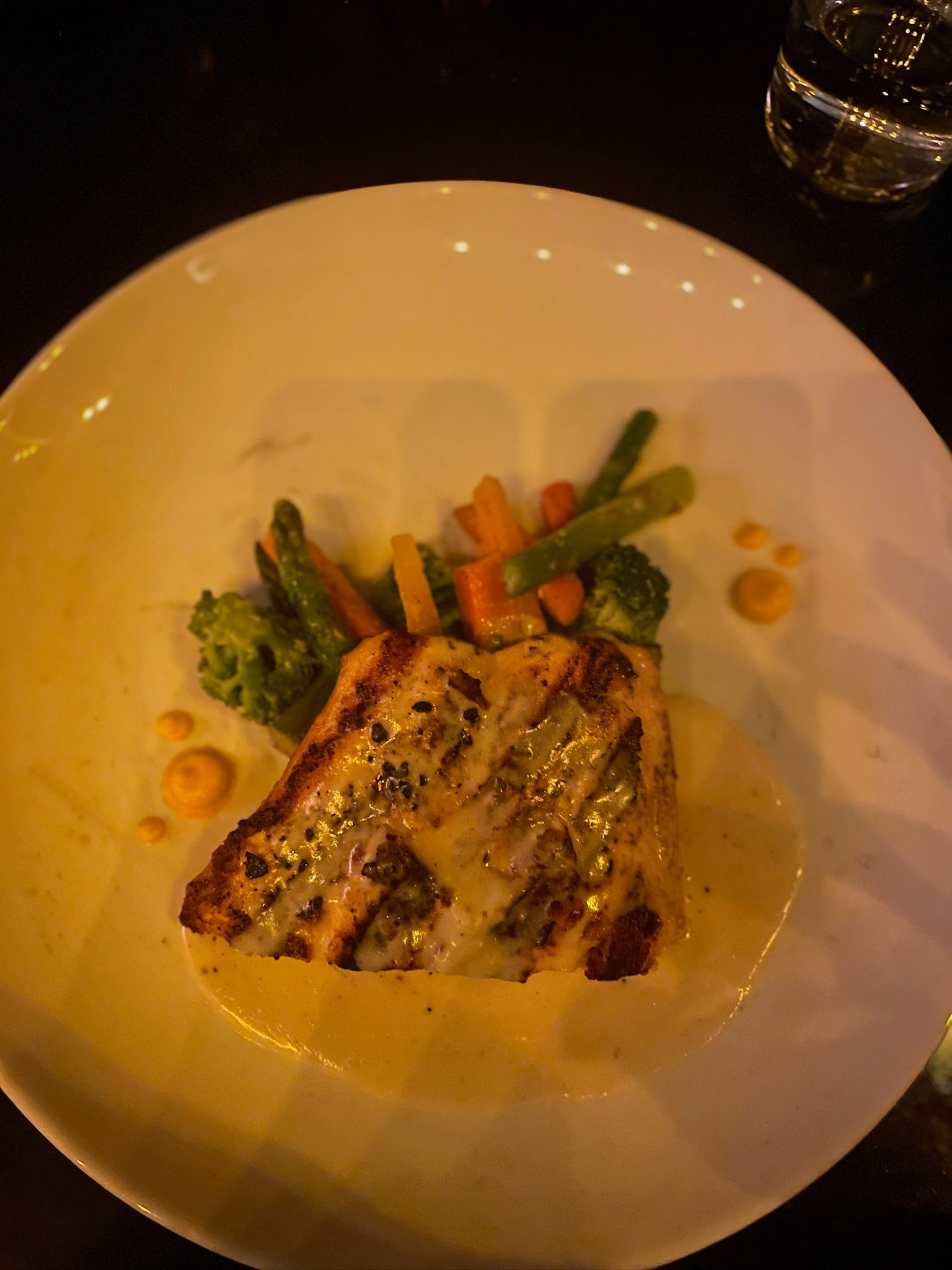 A white plate topped with a piece of meat and vegetables