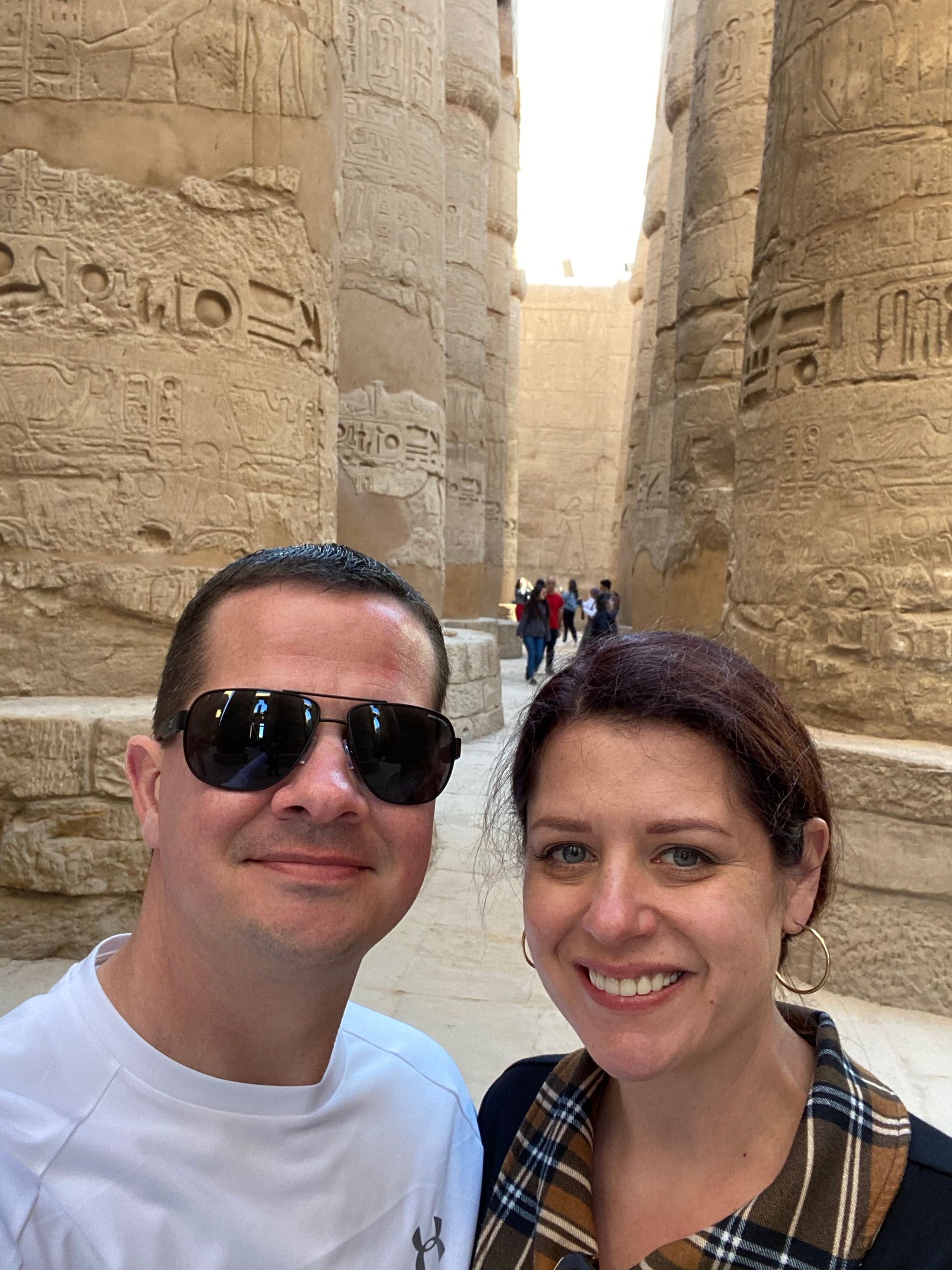 A man and a woman are posing for a picture in front of a stone wall.