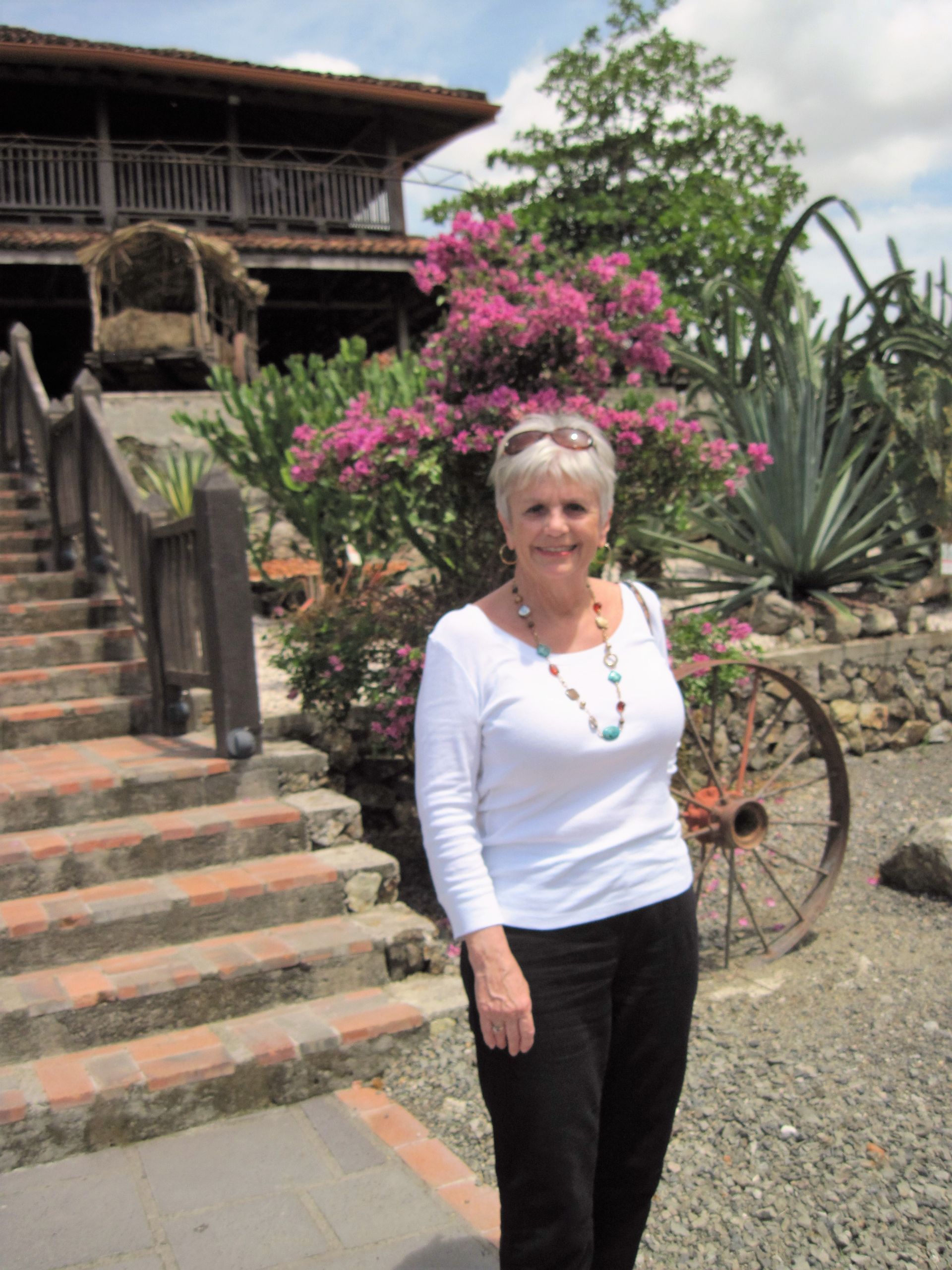 A woman in a white shirt is standing in front of a house