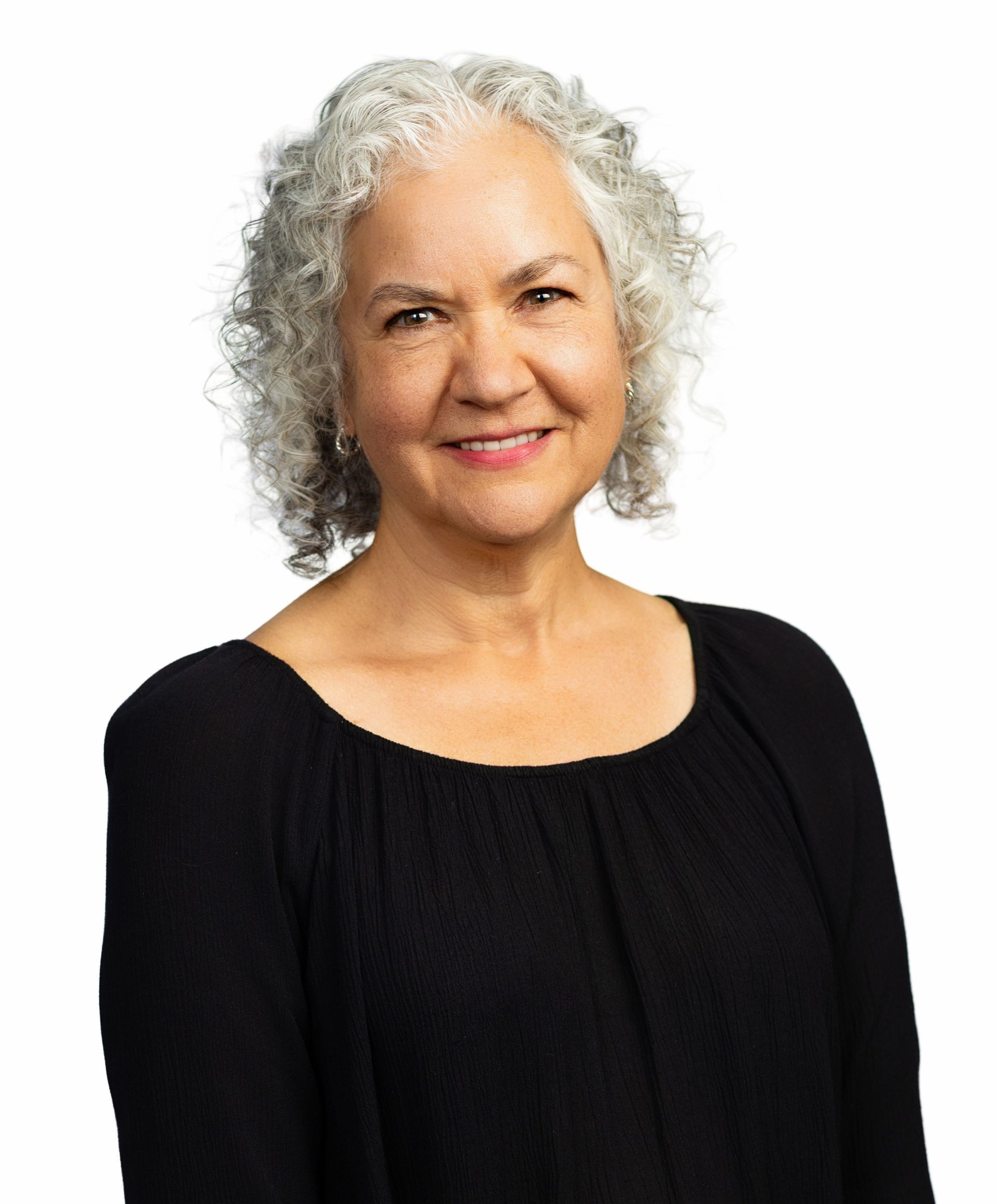 A woman with curly hair and a necklace is smiling for the camera.