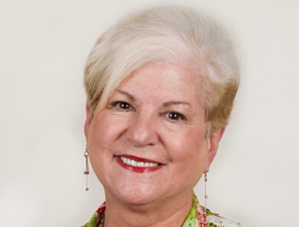 top travel agent of US A woman with white hair and red lips is smiling for the camera.