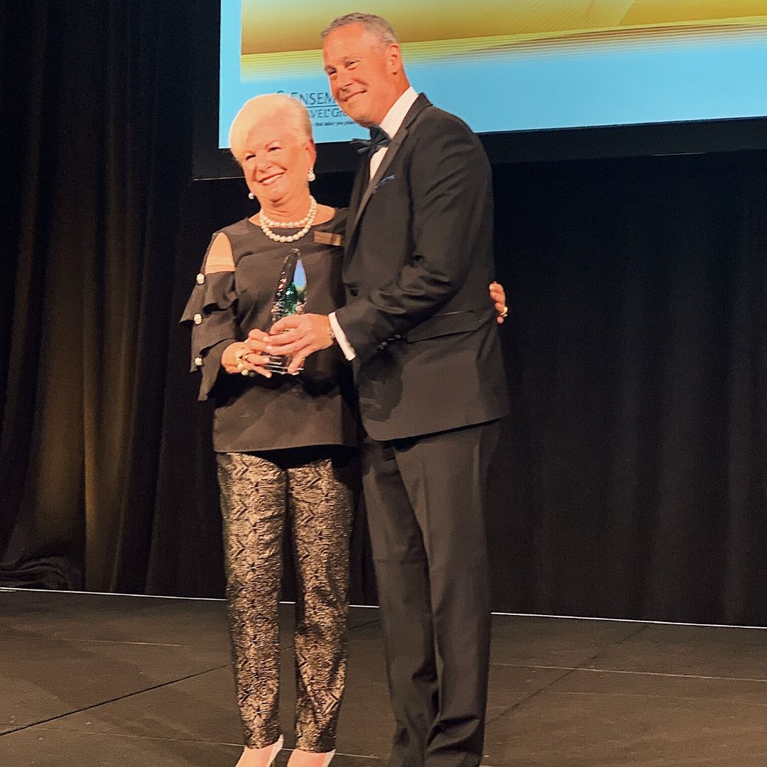 women accepting the warren buckner award A man and woman are standing on a stage holding an award.