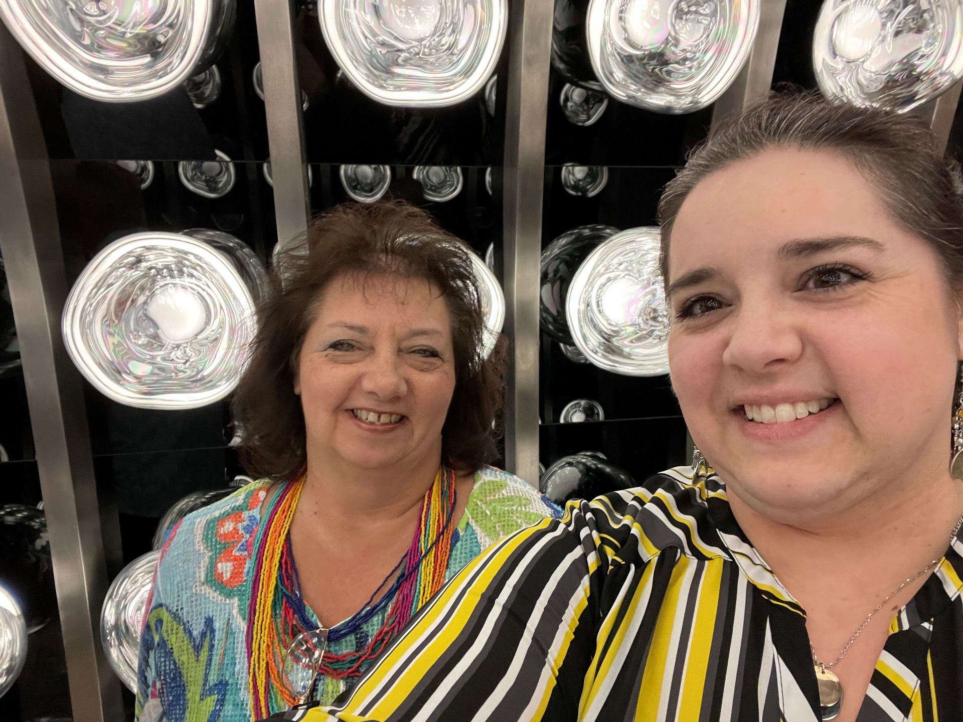 Two women are posing for a picture in front of a wall of lights.