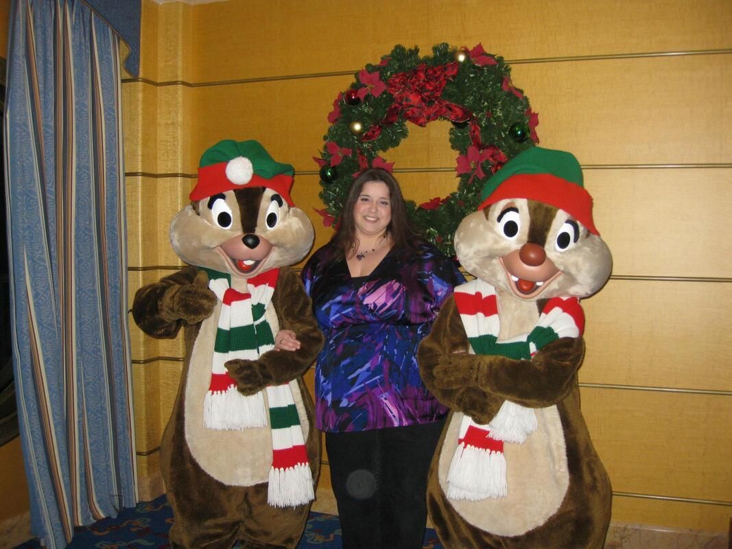 A woman poses with chipmunks wearing christmas hats and scarves