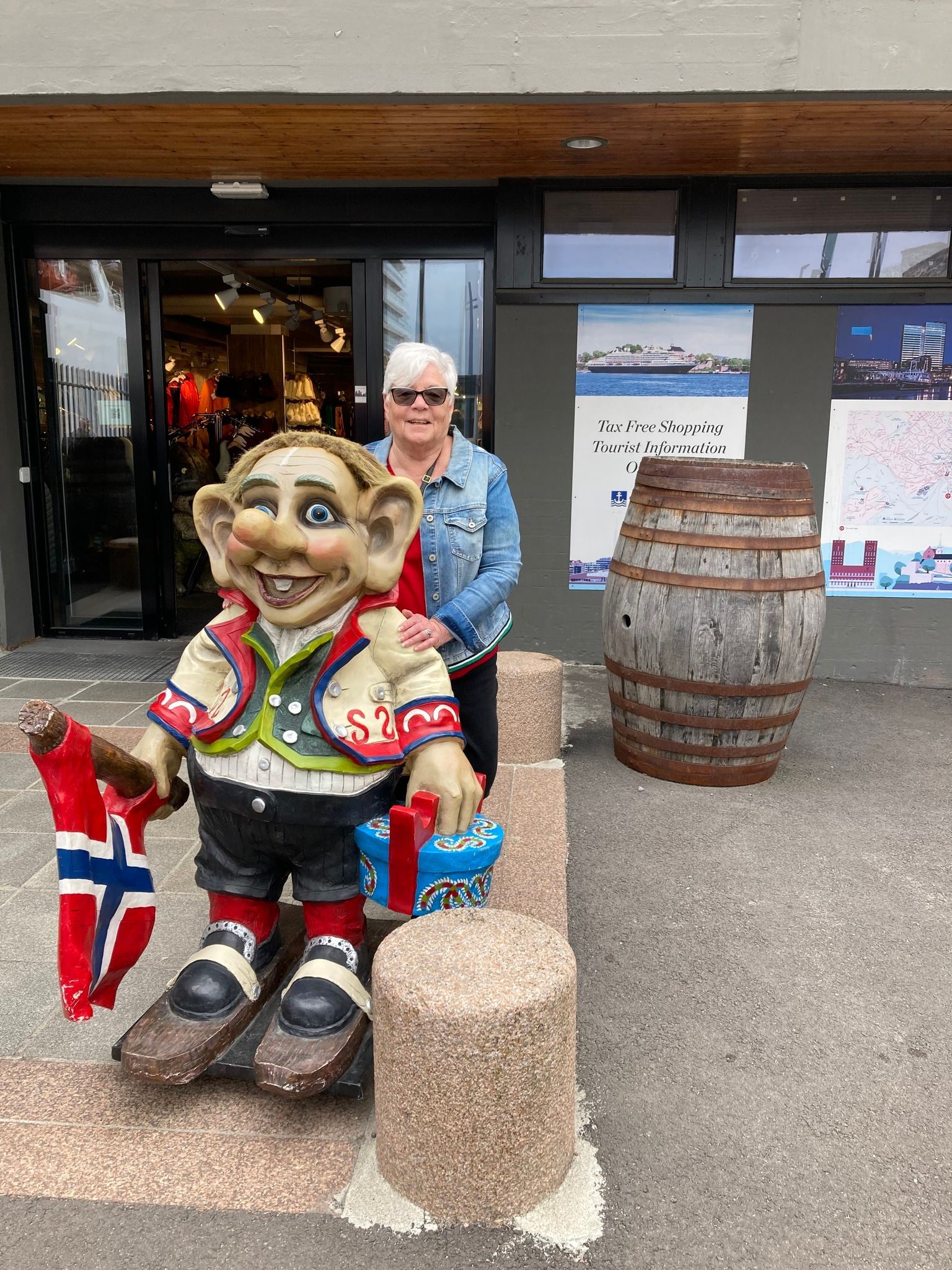 A woman is standing next to a statue of a troll holding a flag.