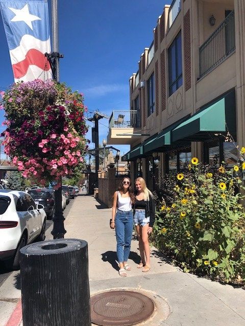 Two women standing on a sidewalk in front of a building