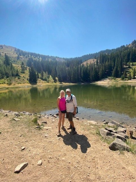 A man and a woman are standing next to a lake.