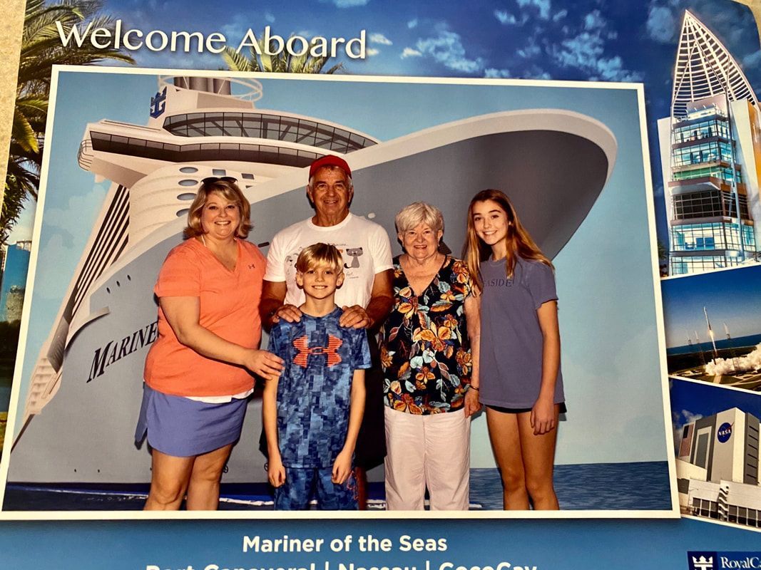 A family posing for a picture in front of a cruise ship