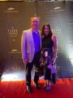 A man and a woman are standing on a red carpet.