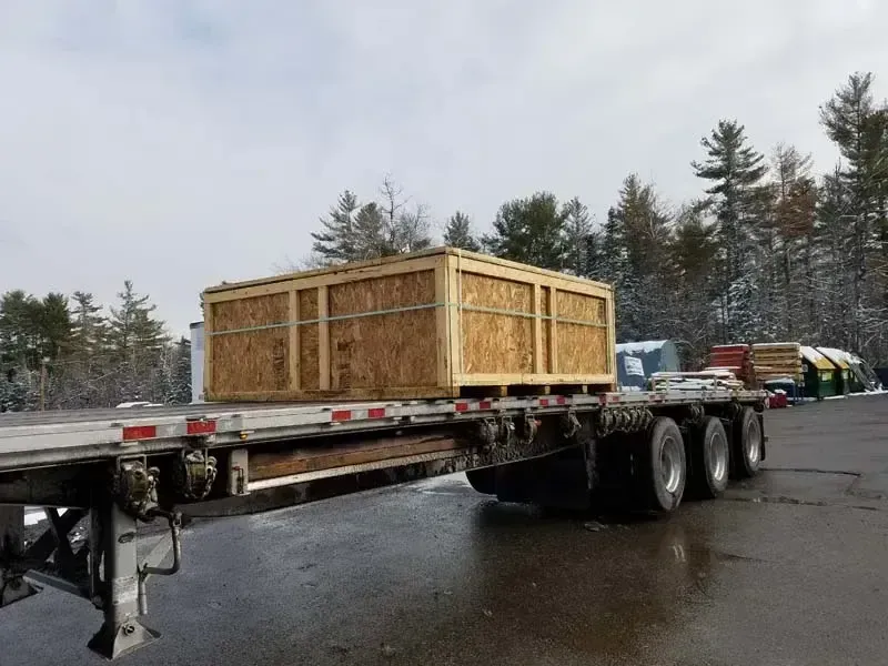 A semi truck is carrying a large wooden box on a trailer.