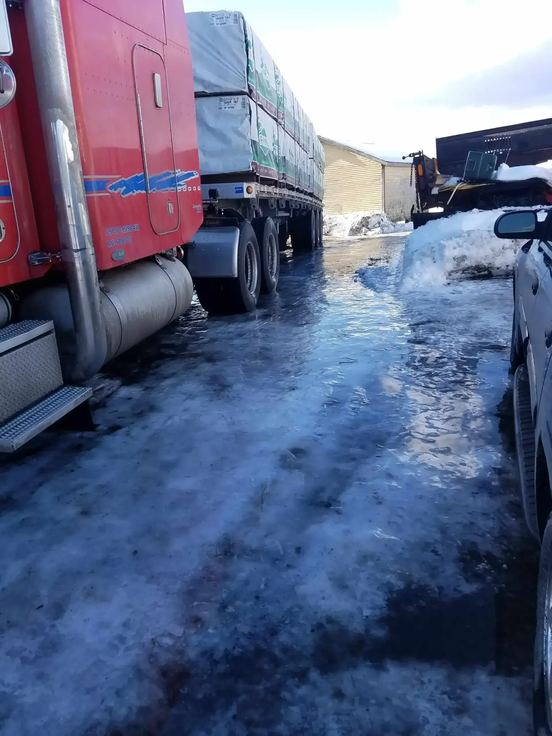 A red semi truck is parked on a snowy road