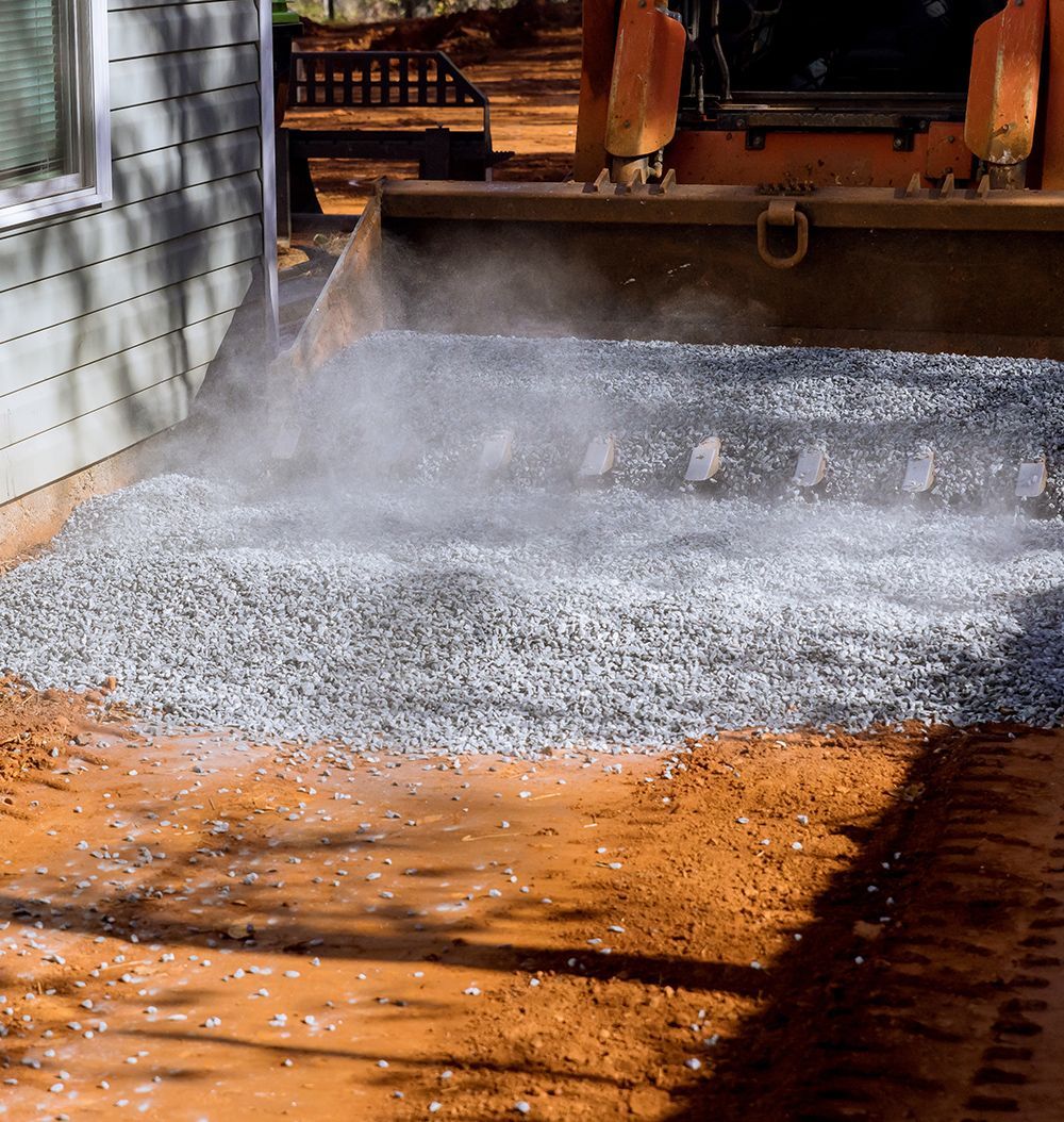 A bulldozer is moving gravel in front of a house