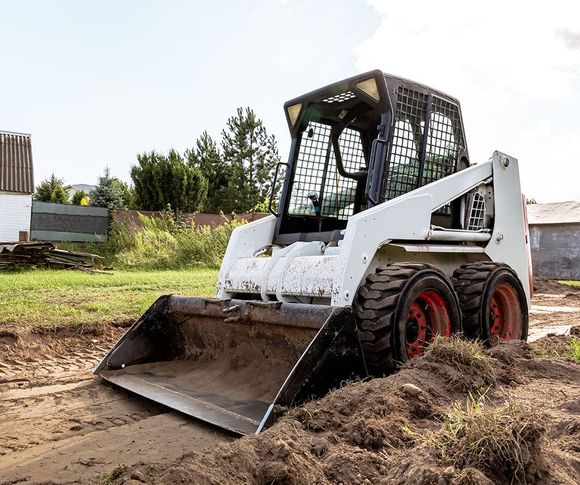 A small bulldozer is sitting on top of a pile of dirt.