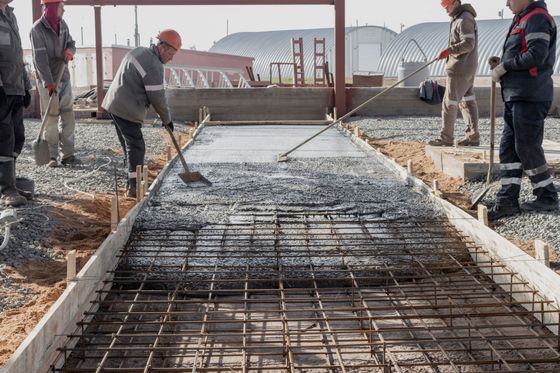 A group of construction workers are working on a concrete road.