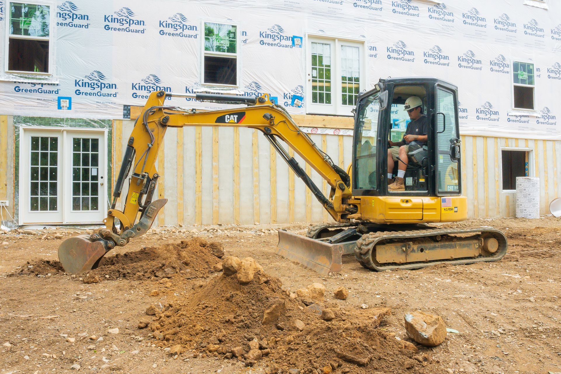 Yellow excavator digging dirt at a construction site, with a worker inside.