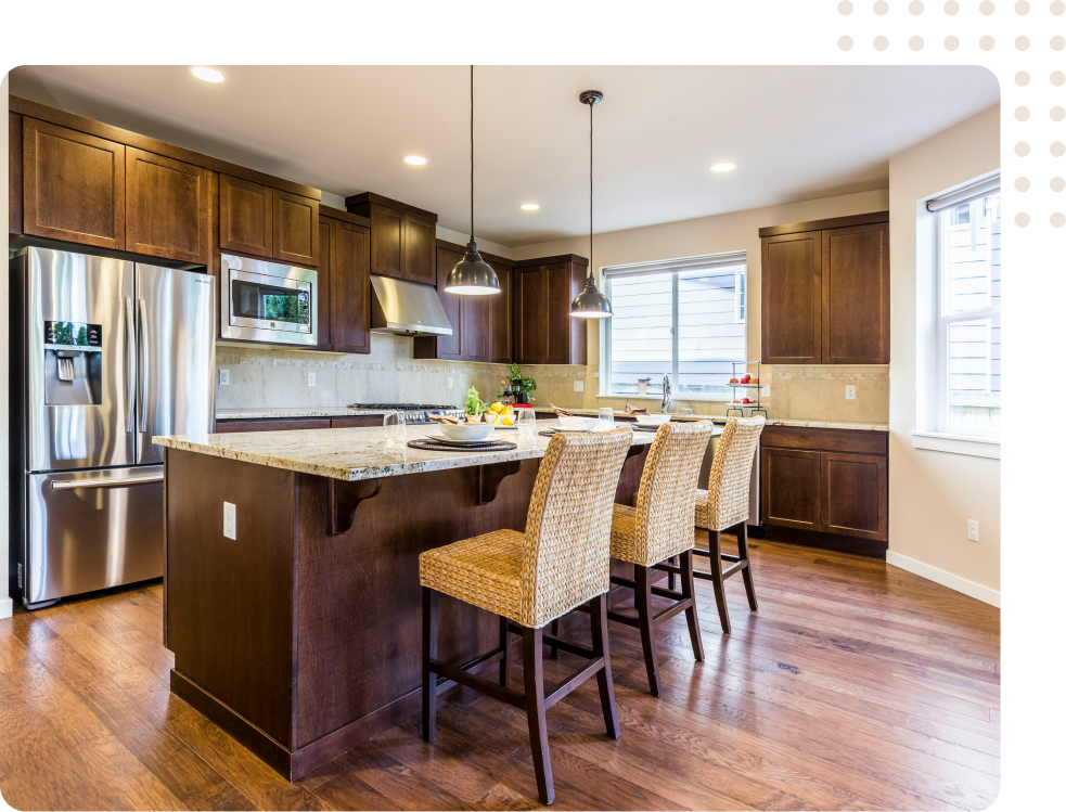 A kitchen with wooden cabinets , stainless steel appliances , a large island , and wicker chairs.