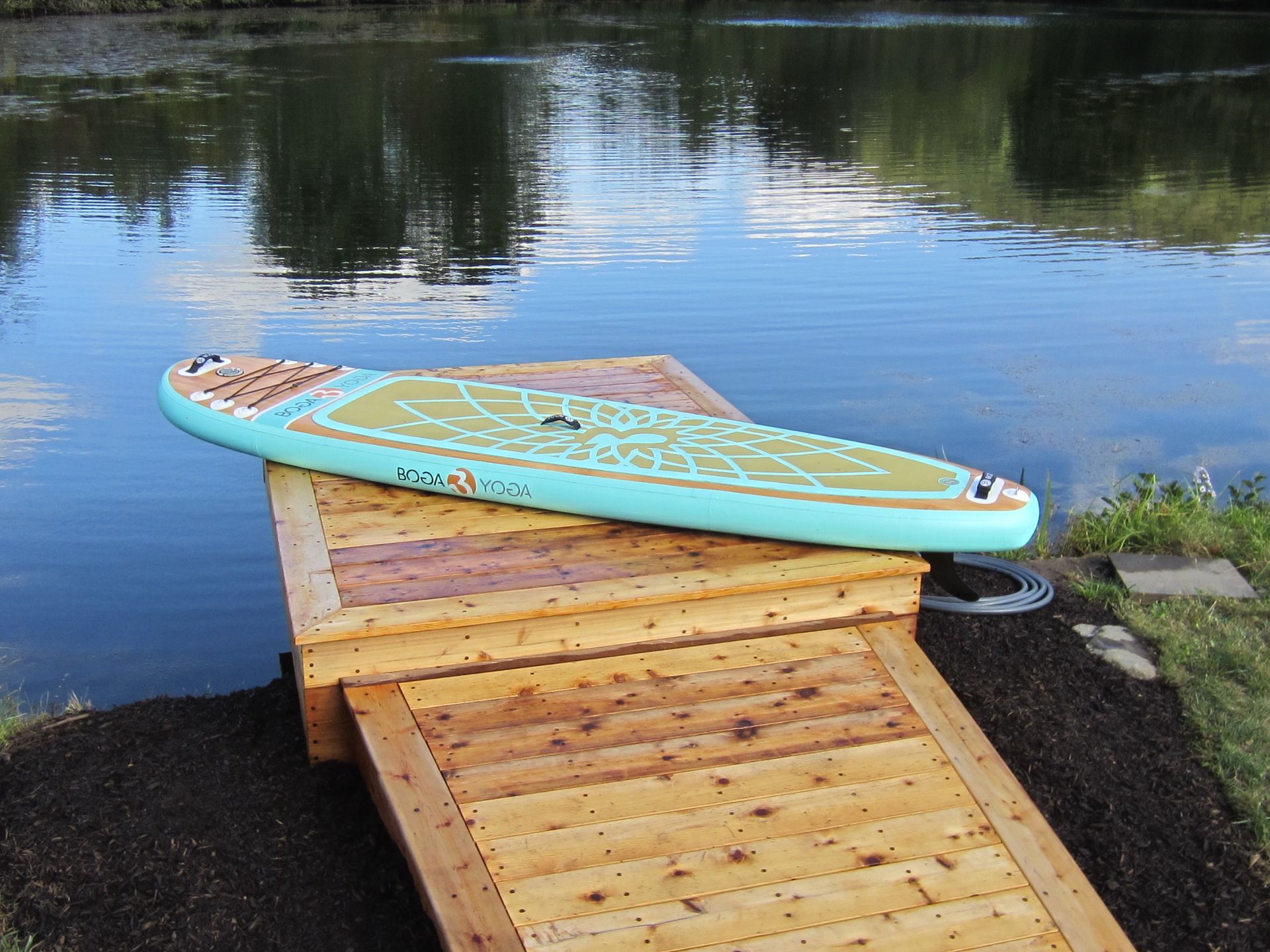 Paddleboard on a wooden dock by a calm body of water.