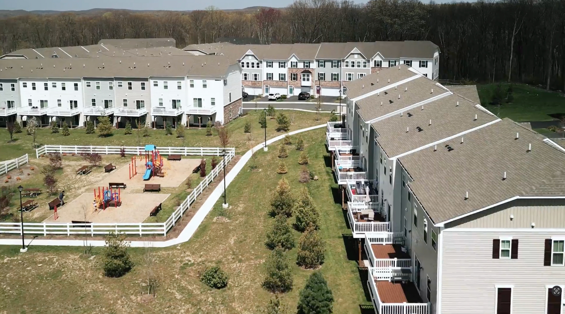 View of a residential complex with townhouses, a playground, and trees; daytime.