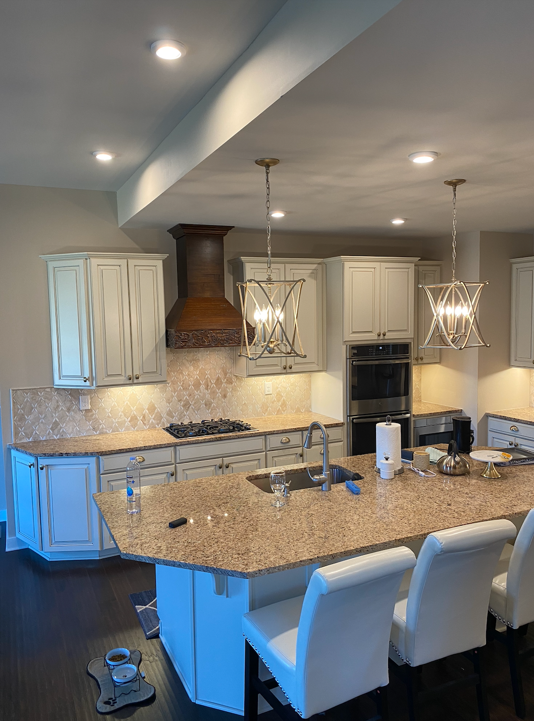 Kitchen with a large island, light cabinets, brown granite countertops, and pendant lights.