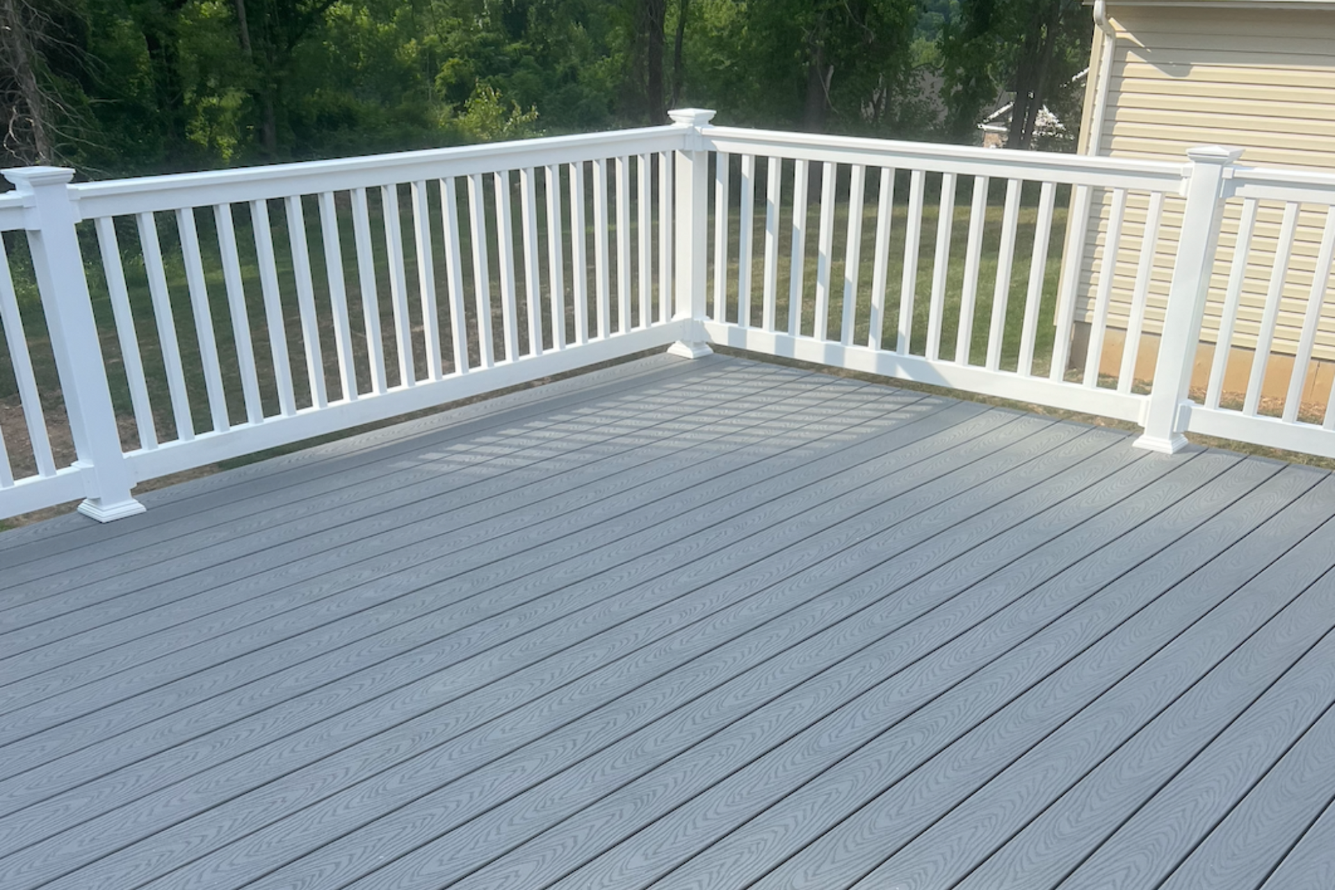 Gray deck with white railing, corner setting, bright sunlight.