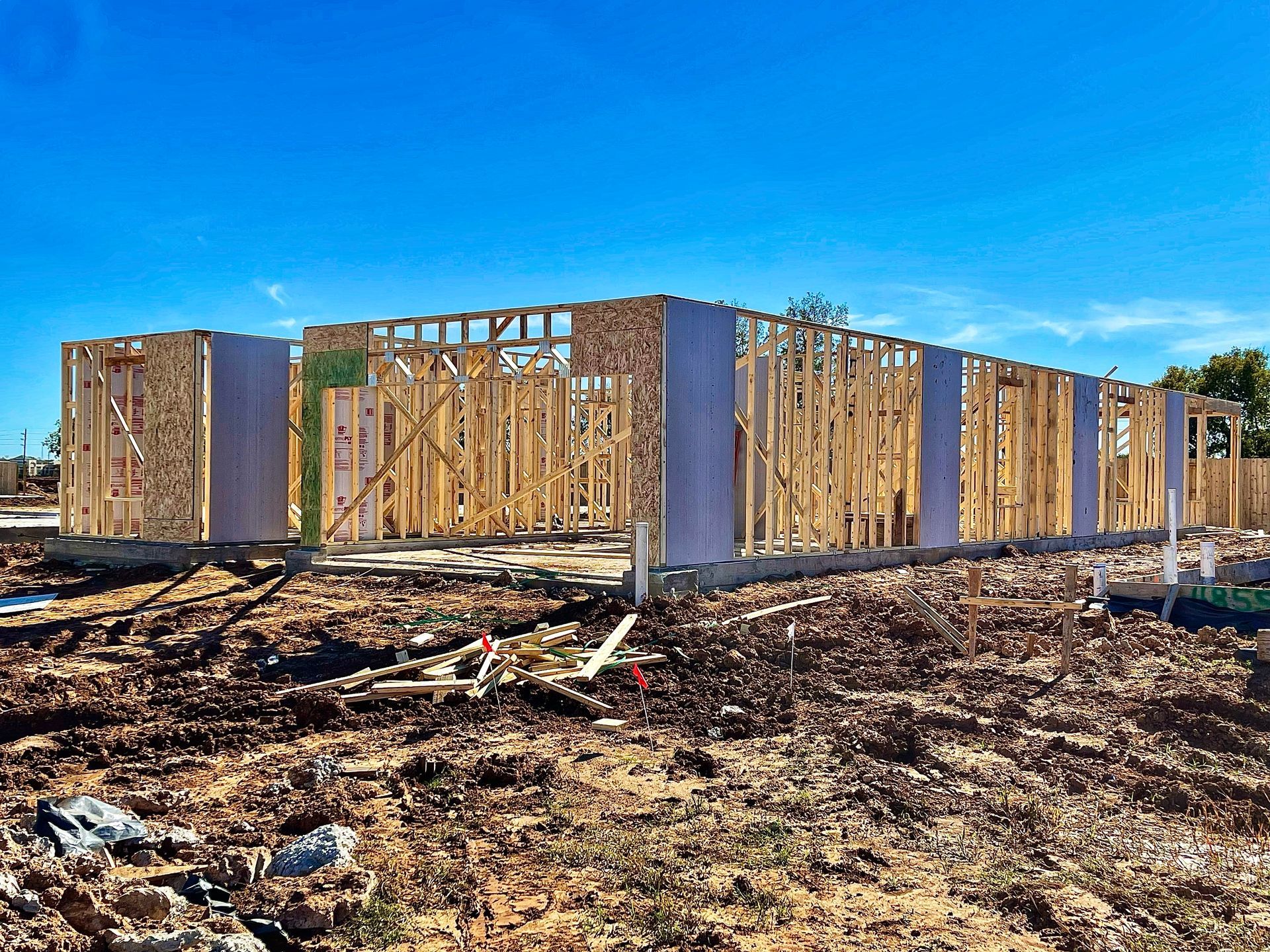 Wooden framing of a house under construction against a bright blue sky.