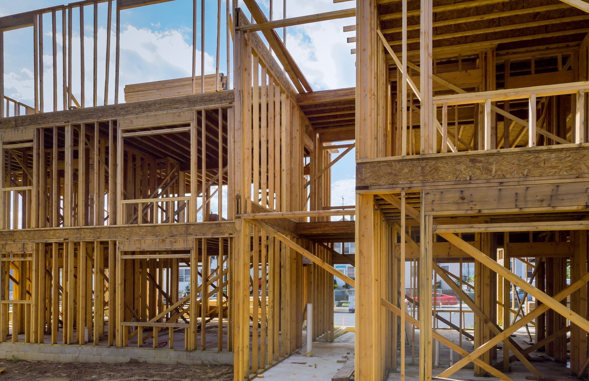 Wooden framing of a multi-story house under construction, with exposed beams and open areas.
