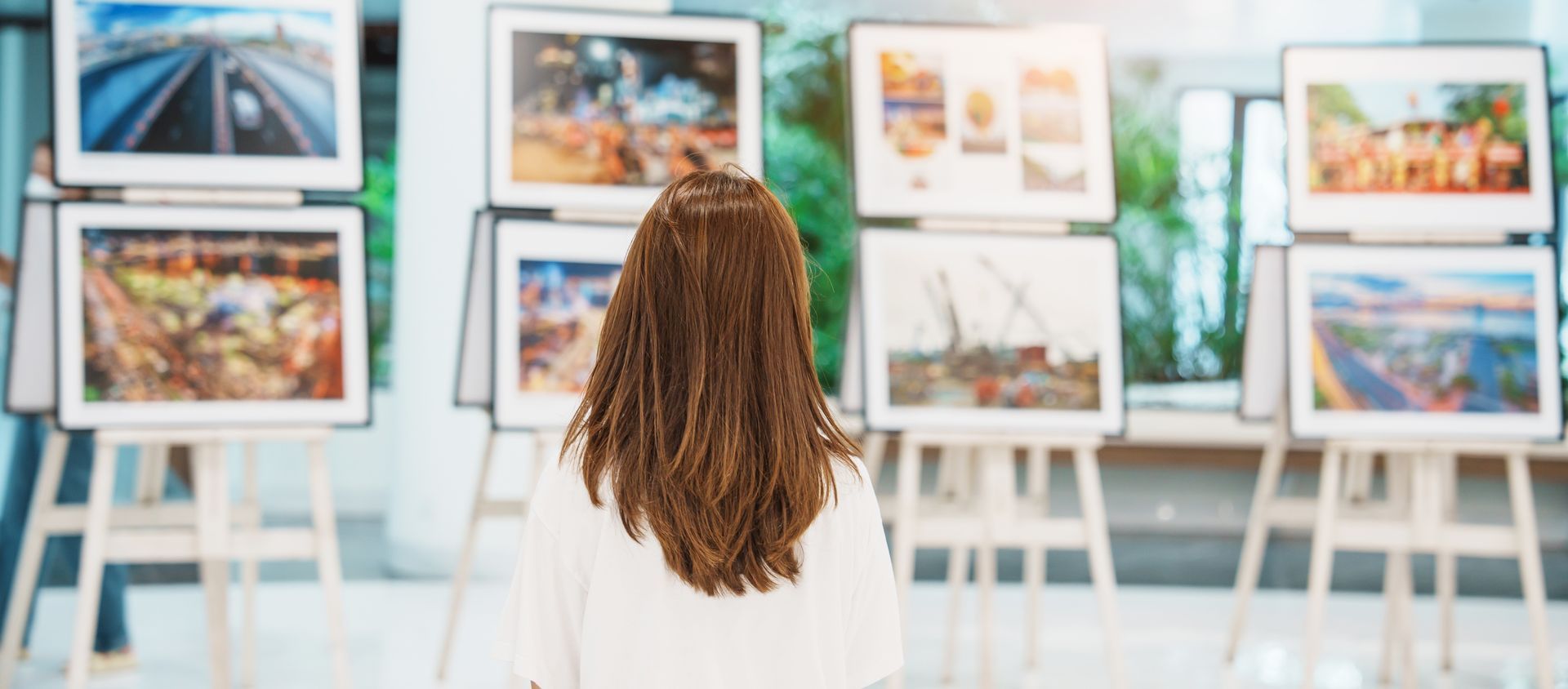 A woman is looking at paintings in an art gallery.