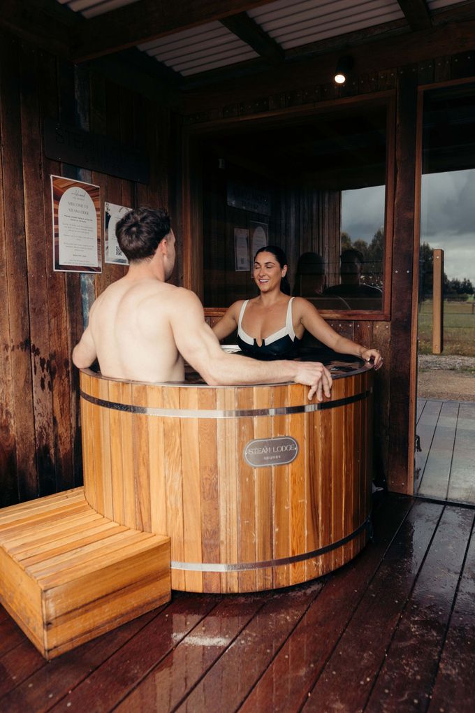 A bedroom with a king size bed , a couch , a table and a bottle of wine.