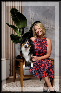 Debbie Taylor with her Miniature Aussiedoodle — North Idaho REALTOR® behind Taylor Connections That Move You Debbie Taylor, smiling in a red and navy dress, sits with her Miniature Aussiedoodle in a modern North Idaho setting. Real estate branding for Taylor Connections is displayed beside her, featuring her tagline “Connections That Move You.”