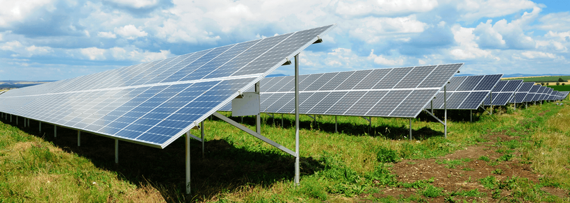 Solar panels in a grassy field against a cloudy sky, showcasing renewable energy.