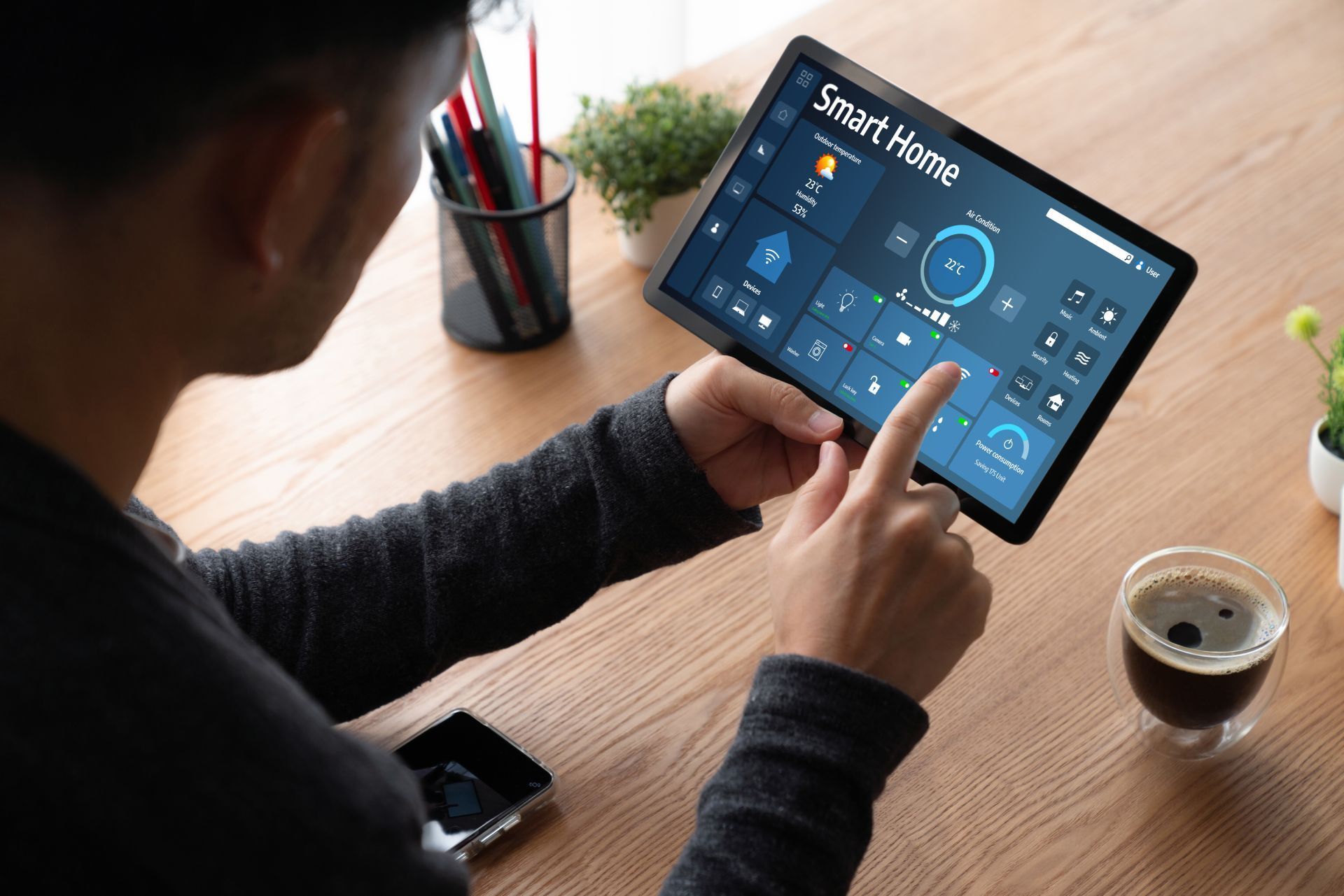 Person using a tablet to control smart home devices; sitting at a desk.