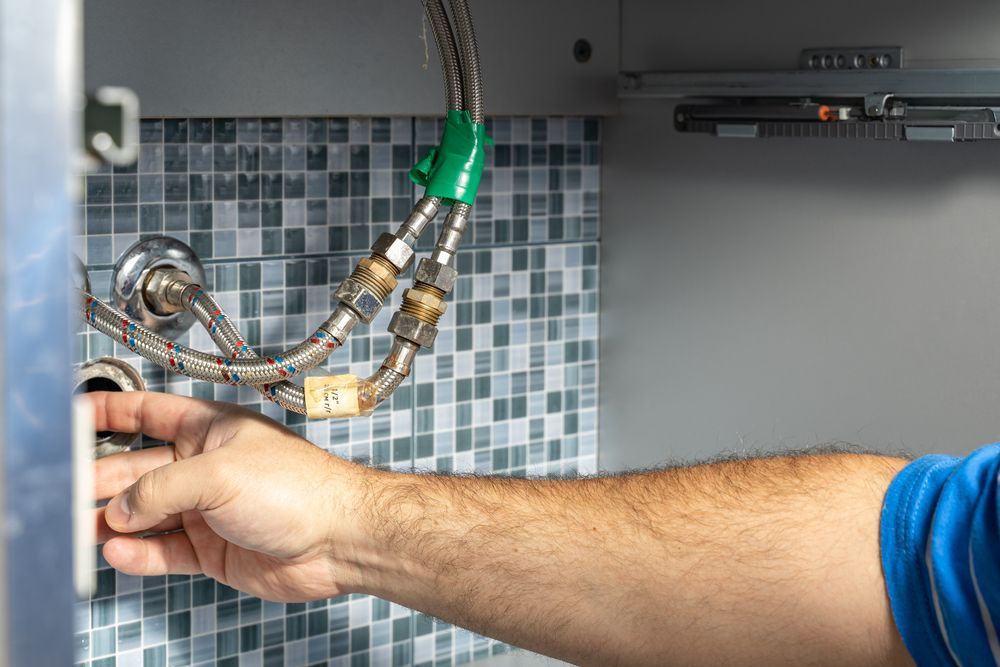 A Man is Fixing a Faucet in a Bathroom — Accredited Plumbing in Dolphin Point, NSW