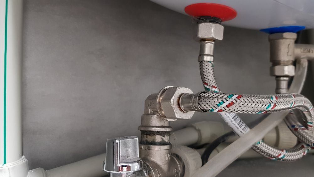 A Close Up of a Water Heater With a Hose Attached to It — Accredited Plumbing in Kings Point, NSW