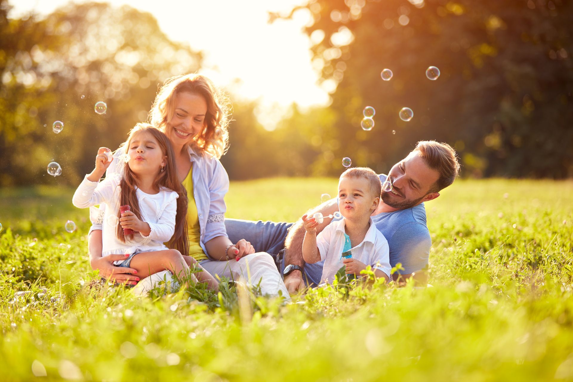 A Family is Sitting in the Grass Blowing Soap Bubbles