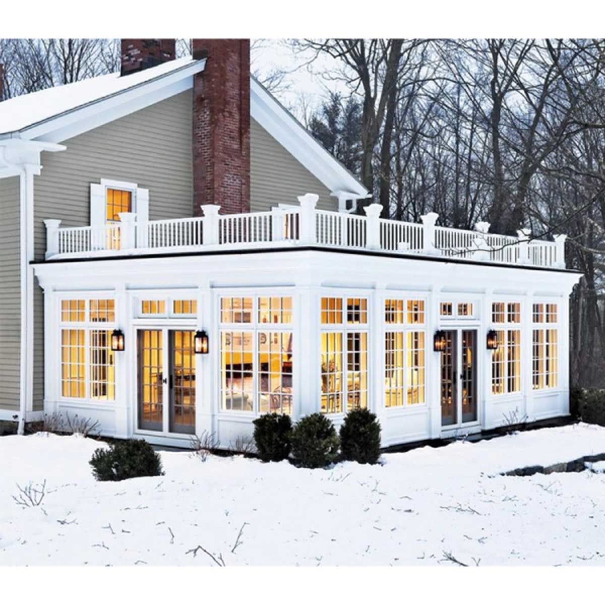 A house with a lot of windows and a balcony in the snow