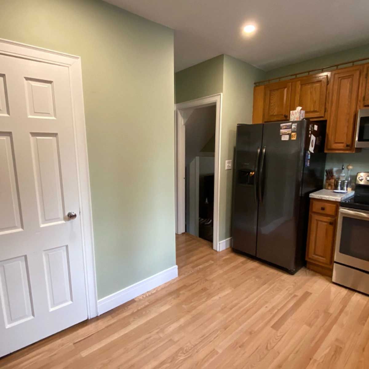 A kitchen with a stainless steel refrigerator and wooden cabinets