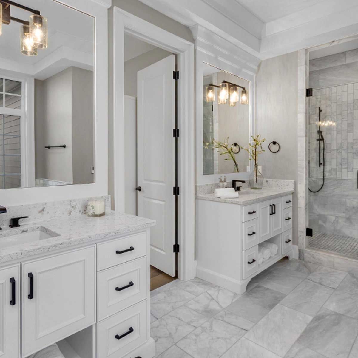 A bathroom with two sinks , a mirror and a shower.
