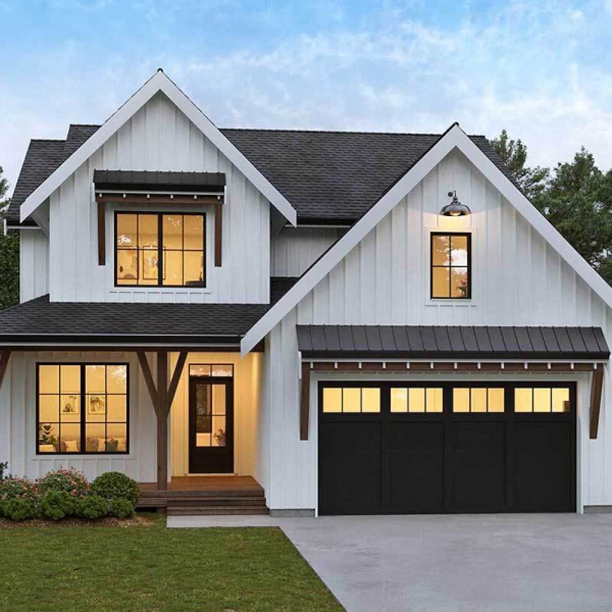 A white house with a black garage door and a black roof.
