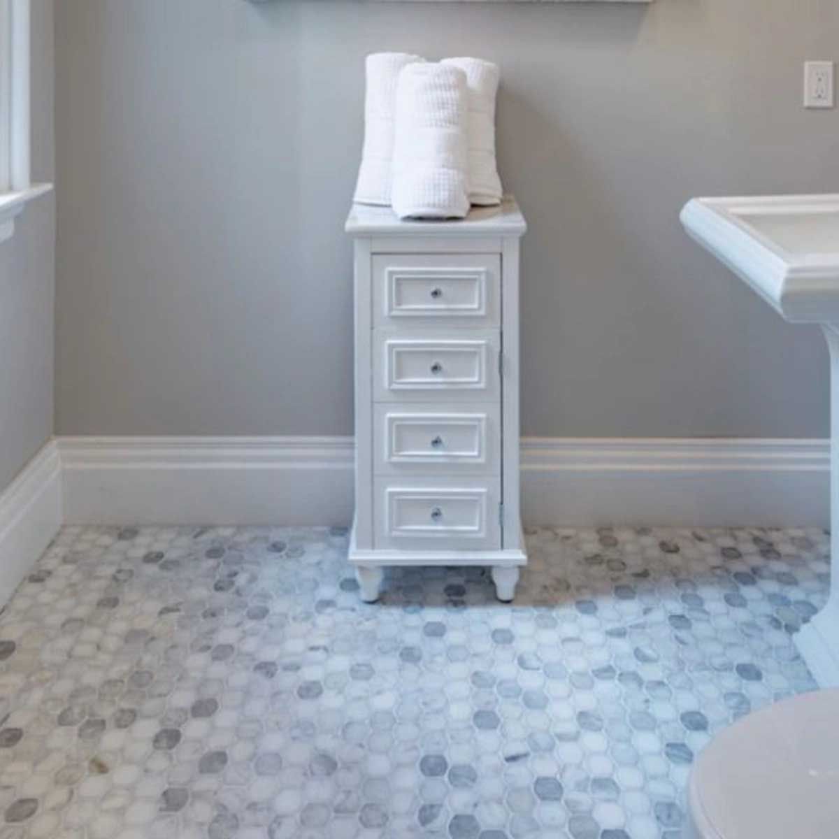 A bathroom with a sink and a dresser with towels on top of it.